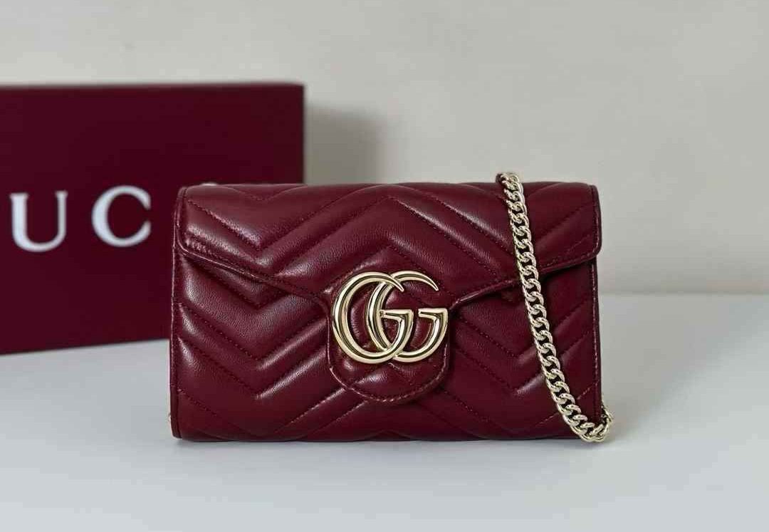 WhatsApp Image 2025-06-28 at 14.33.12 (1) Black Gucci Marmont Mini Bag, featuring quilted leather, a prominent gold GG logo, and a chain strap, next to a red Gucci box.