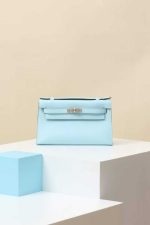 Light blue Hermès Kelly Pochette leather clutch bag on pedestal