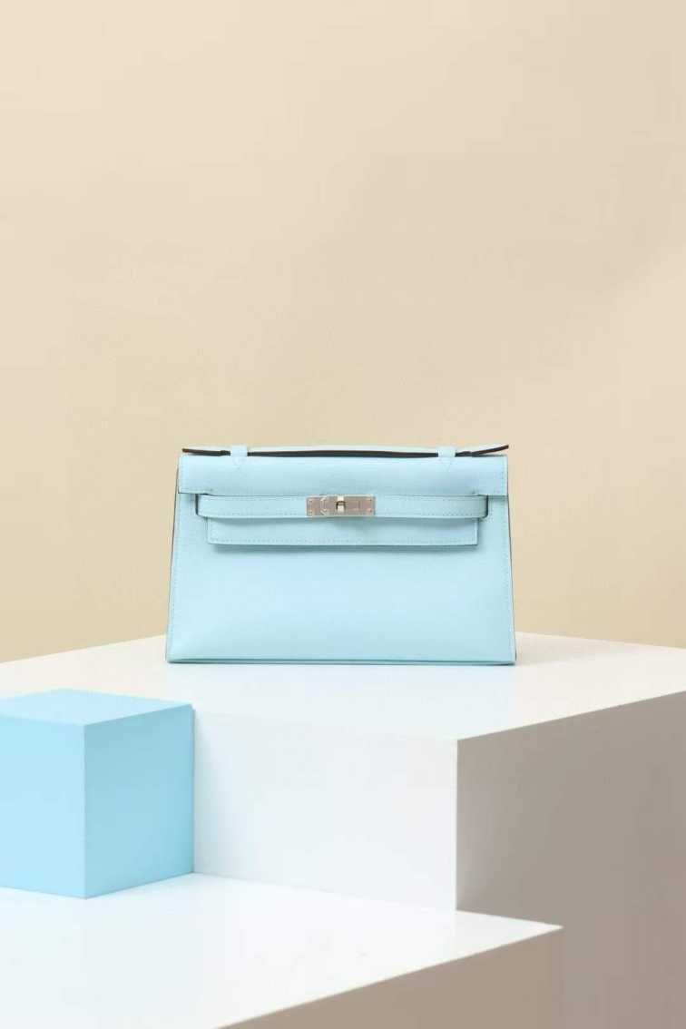 WhatsApp Image 2025-07-10 at 18.15.20 (1) Light blue Hermès Kelly Pochette leather clutch bag on pedestal
