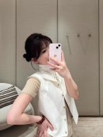 A front view of a women's white tailored vest with intricate gold button details.