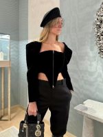 A full-length shot of a woman in a black velvet top and a beige skirt
