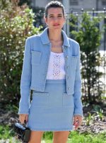 A model is wearing a full-length, elegant light blue tweed skirt suit set. The outfit consists of a cropped, collarless jacket with button details and a matching A-line skirt.