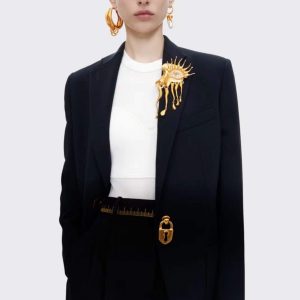 Model wearing an elegant black blazer with a unique gold brooch and stylish accessories.